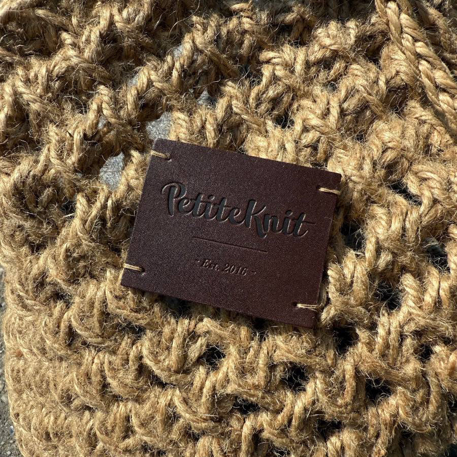 Dark brown leather label with text "PetiteKnit. Est. 2016"