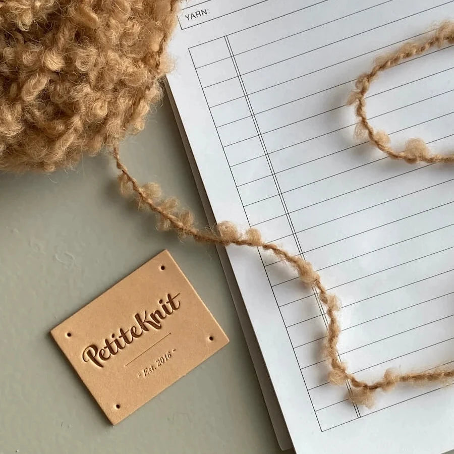 Light brown leather label with text "PetiteKnit. Est. 2016"
