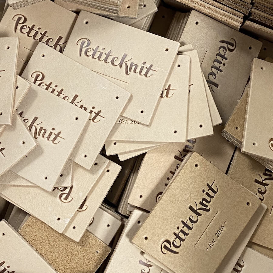 Light brown leather label with text "PetiteKnit. Est. 2016"