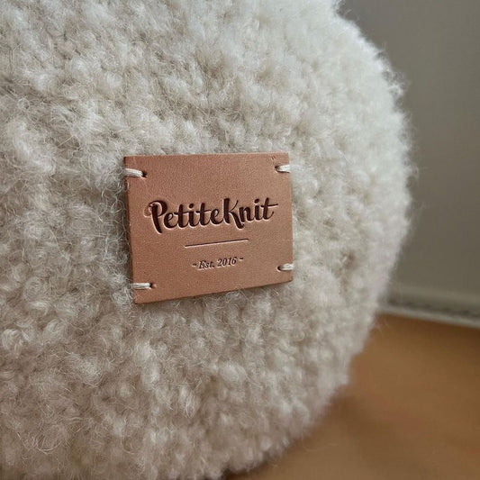 Light brown leather label with text "PetiteKnit. Est. 2016"